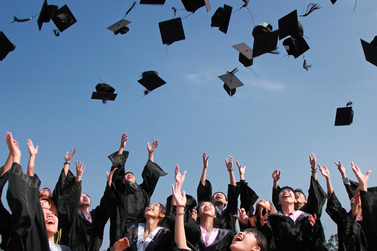 Scholars throwing mortar board hats in air